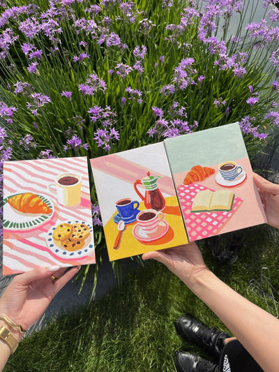 Four finished mini canvases held up in a lavender field